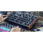 Novation Peak synthesizer with a sleek black control panel, multiple knobs, and digital display showing various sound settings.