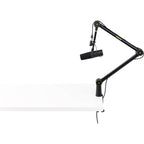 Shure SH-BROADCAST1 broadcast microphone arm mounted on a desk, adjustable arm with sleek black finish for professional audio setups.