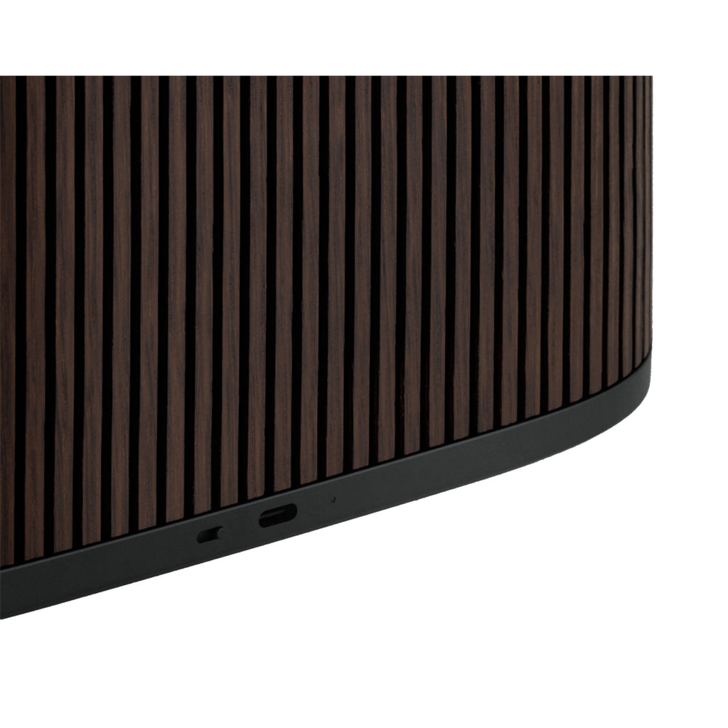 Bang & Olufsen Beosound A5 portable speaker with sleek design, control buttons, and fabric grille in a stylish setting.