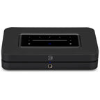 Bluesound Node 2025 black music streamer connected to audio equipment, showing sleek compact design and front display panel.
