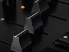 Close-up of Intech Studio PBF4 Series 3 MIDI controller with linear mechanical faders and controls.