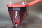 Ortofon 2M Red Verso turntable cartridge mounted on a record player, showcasing its sleek design and stylus.