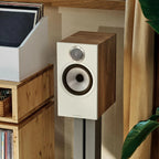 Bowers & Wilkins 606 S3 passive bookshelf speakers in oak finish, showcasing sleek design and speaker grille on a lifestyle setup