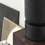 Bang & Olufsen Beosound Balance wireless speaker with sleek design and fabric covering, placed on a wooden surface.
