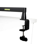 Shure SH-BROADCAST2 broadcast microphone arm mounted on a desk, adjustable with sleek metal design and cable management features.