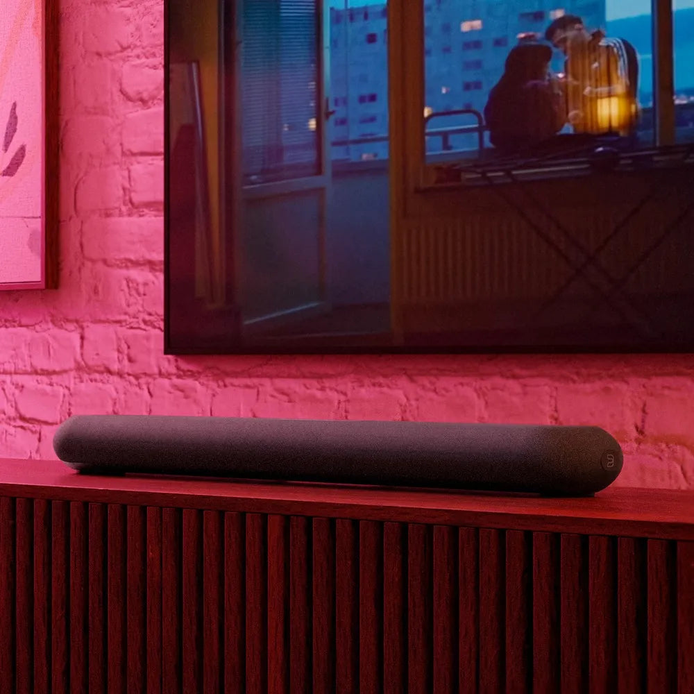 Bluesound Pulse Cinema Mini soundbar with sleek black design, placed below a flat-screen TV for enhanced audio experience.