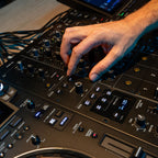 AlphaTheta DJM-V5 DJ mixer with multiple control knobs, faders, and digital display for professional music mixing.
