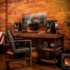 Klipsch R-41PM active bookshelf speakers with wood finish and front control panel, positioned on a modern audio setup.