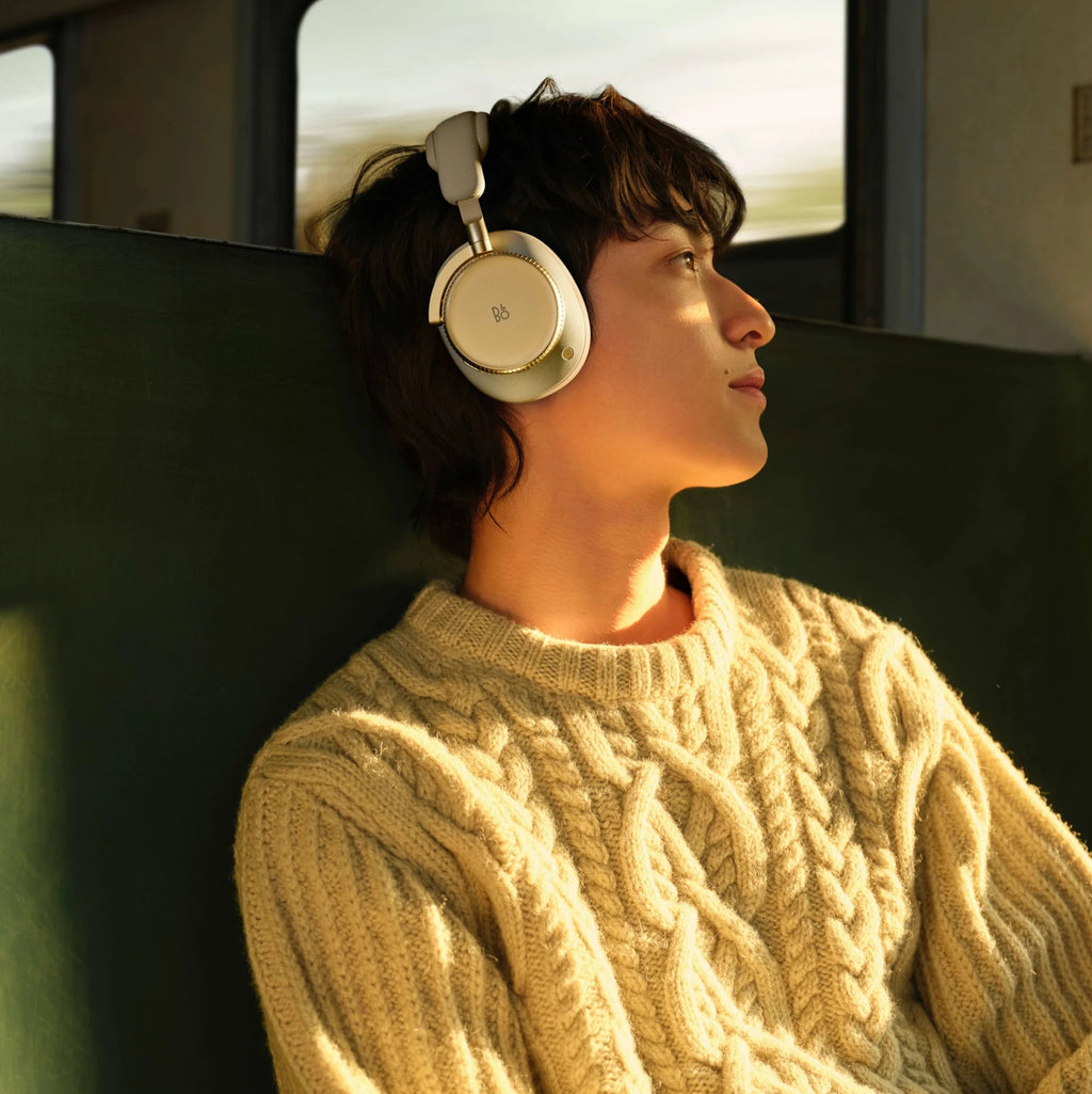 Wireless Bang & Olufsen Beoplay H100 headphones worn around the neck in a lifestyle setting, showcasing sleek black design and comfort.