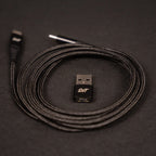 Sim'n Tonic Nome II MIDI interface with rolled USB cable and adapter, showcasing the compact design and connectivity options.