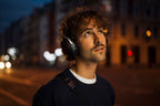 Wireless Beyerdynamic Aventho 300 headphones worn by a city guy in dark lighting, showcasing their sleek design.