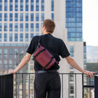 Wandrd Rogue Sling video equipment bag in Rhone Burgundy, compact design with adjustable strap and multiple compartments.