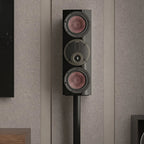 DALI Rubikore Cinema center speaker placed on a living room shelf, showcasing sleek black design and compact size.