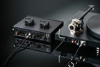 Pro-Ject Tube Box S3 B phono preamp with vacuum tubes, compact black design, featuring input and output connections for audio enhancement.