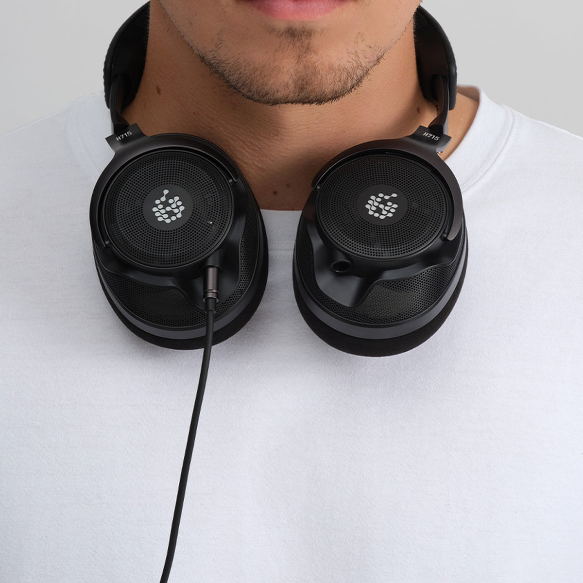 Adam Audio H715 Reference headphones worn around the neck, lifestyle shot