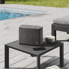 Audio Pro A15 portable speaker shown outdoors with rugged design, matte finish, and control buttons on top.