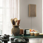 Bang & Olufsen Beosound Level wireless speaker in kitchen with wooden finish, compact and modern design.