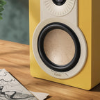 DALI Kupid passive bookshelf speakers in vibrant yellow finish, showcasing their compact design and sleek aesthetic.