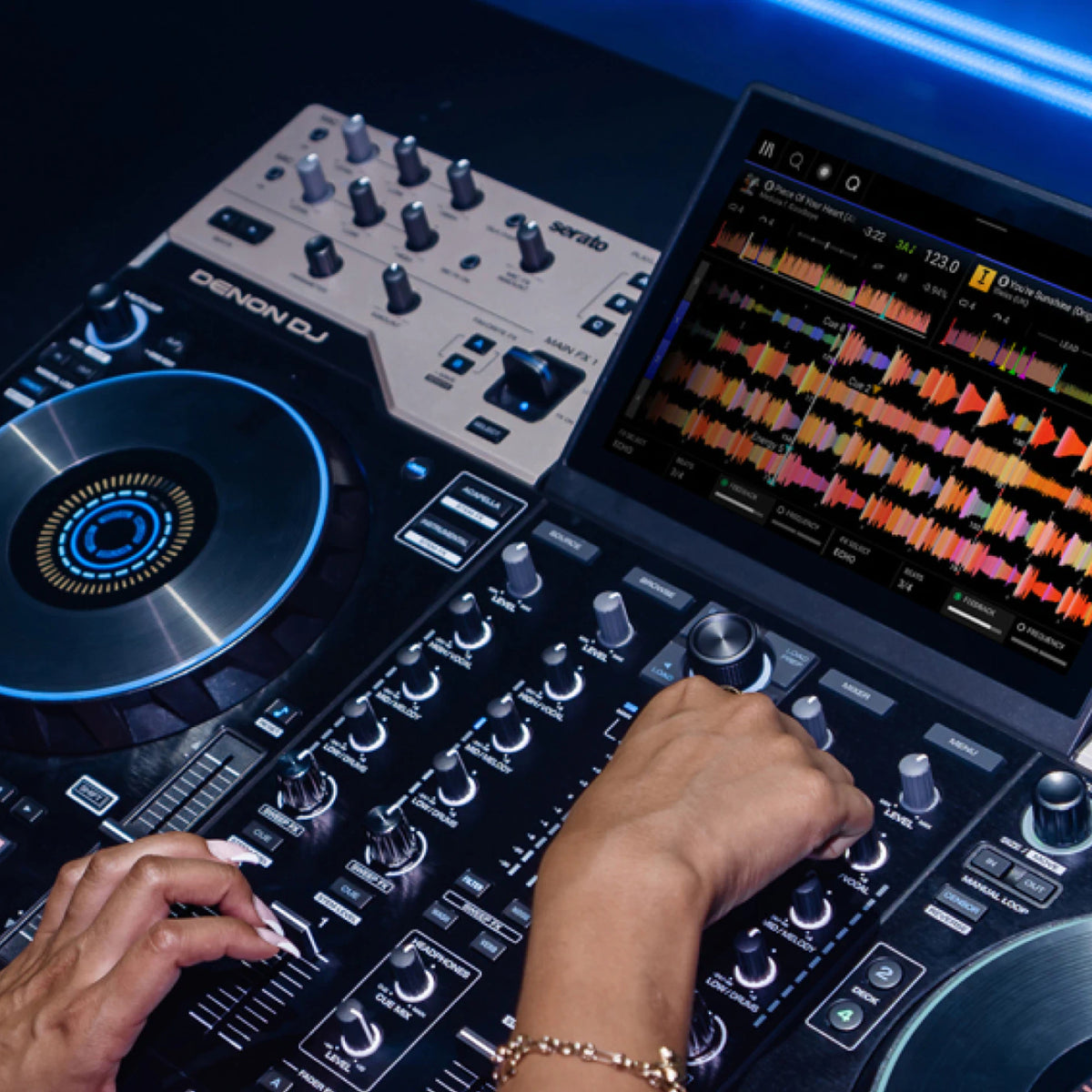 Denon DJ Prime 4 G2 four-deck standalone DJ system with waveform touchscreen and lit jog wheel in a club booth