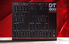 Dtronics DT-800 synthesizer with multiple knobs and controls, featuring a sleek black design and digital display.