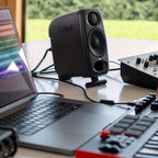 IK Multimedia iLoud Micro Monitor Pro active nearfield speakers on a studio desk with controls and cables visible.