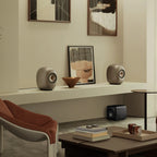 KEF LS Luxe in Dusk Titanium on a living room shelf with artwork and a KEF subwoofer