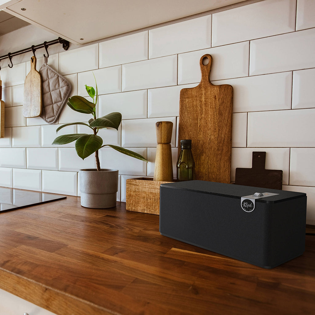 Klipsch The Three Plus wireless speaker, lifestyle on a wooden shelf in black