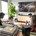 Klipsch Flexus SURR 100 soundbar behind friends hanging out, showcasing sleek design and speaker grille for home entertainment.