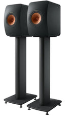 Pair of KEF S2 speaker stands in carbon black holding KEF LS50 Wireless II speakers, front view with spikes on a floor.