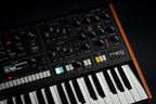 Moog Muse synthesizer with black background showing its control panel and vintage-style knobs and switches