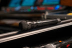 Shure Nexadyne 8/C dynamic microphone with a rugged design, shown in an outdoor environment for professional audio use.