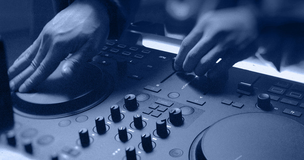 Native Instruments Traktor MX2 DJ controller with dual jog wheels, colorful performance pads, and various control knobs and faders.