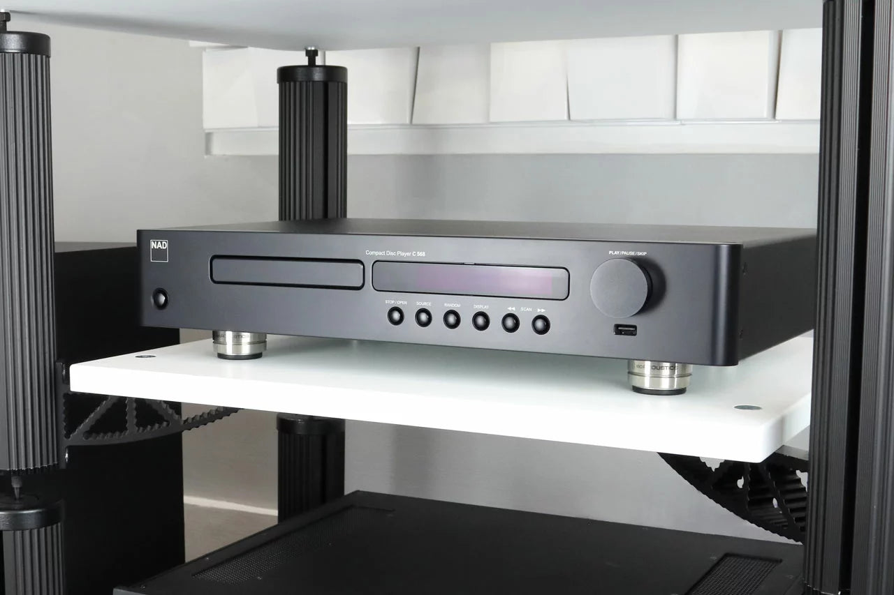 IsoAcoustics Orea Indigo speaker stands on a modern living room floor, showcasing their sleek design and sturdy build.