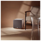 Q Acoustics Q SUB80 subwoofer showing a sleek black design with a textured finish and a circular speaker grille.