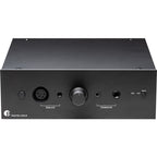 Pro-Ject Head Box DS3 B headphone amplifier and DAC with sleek black design and control knobs, set on a wooden surface.