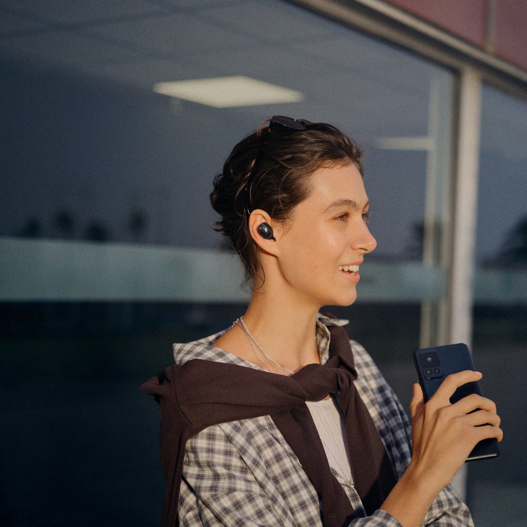 Woman using her phone outdoors wearing Sennheiser Momentum True Wireless 5