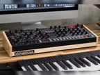 Sequential Trigon-6 desktop synthesizer with black knobs, orange and gray interface, and multiple control buttons on a white background.