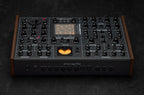 Erica Synths SYNTRX II desktop synthesizer with knobs, buttons, and colorful LED display on a black surface.